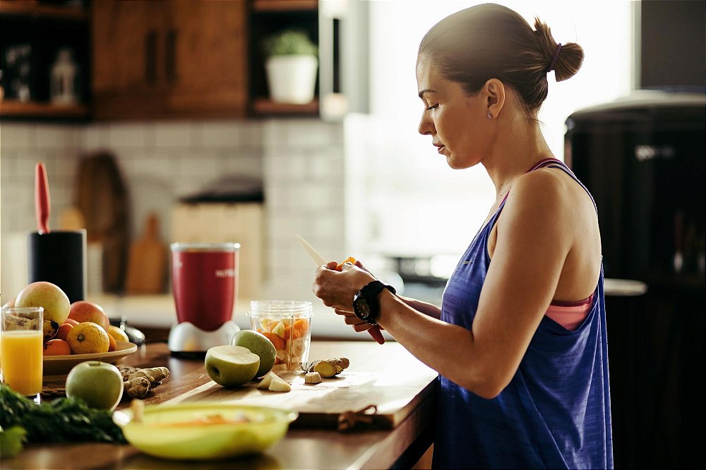 Mulher preparando um smoothie proteico de frutas e Whey Protein Concentrado Soldiers Nutrition