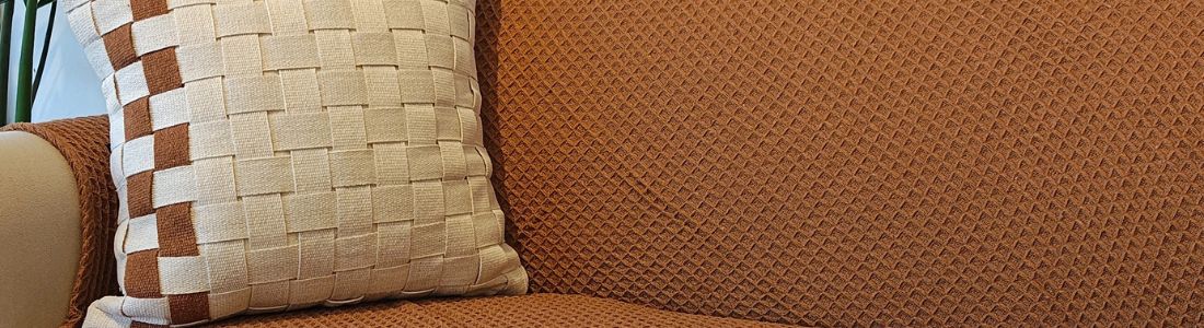 Sala aconchegante com almofadas, manta caramelo e tapete artesanal em tons terrosos