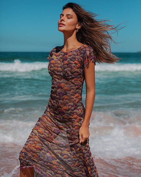 modelo na praia com saída de praia longa, vestido de tule estampado roxo com conchas