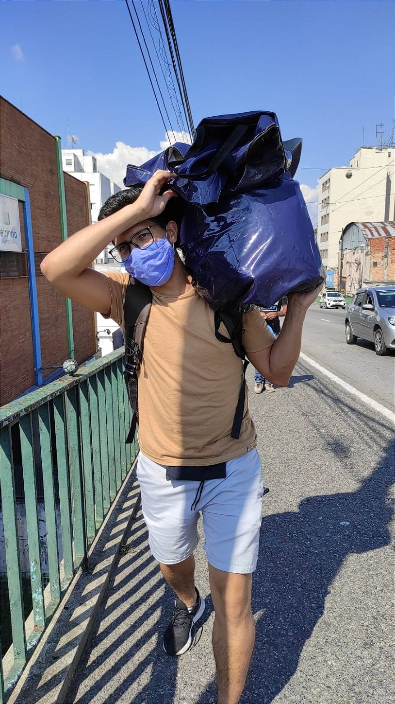 Denis carregando uma sacola grande de mercadorias no ombro