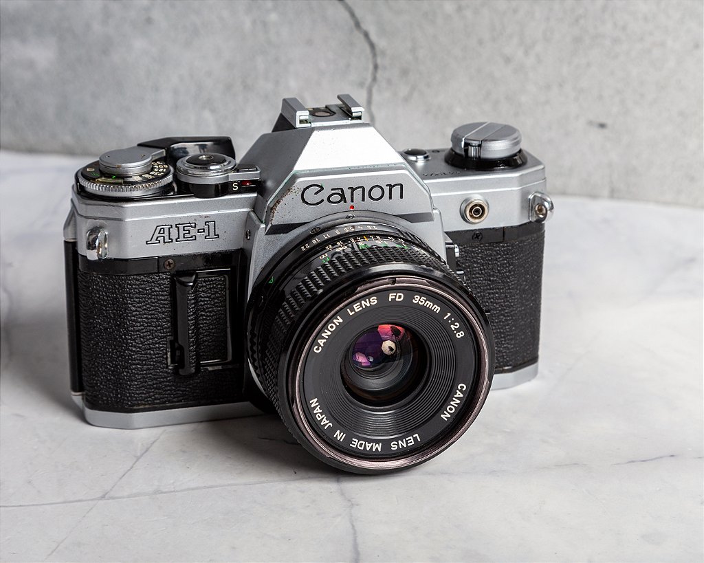 Câmera 35mm - Canon AE-1 (9/10)+ Lente 35mm f2.8 (8.8/10)+ Câmera 35mm - Canon AE-1 (9/10)+ Lente 35mm f2.8 (8.8/10)+