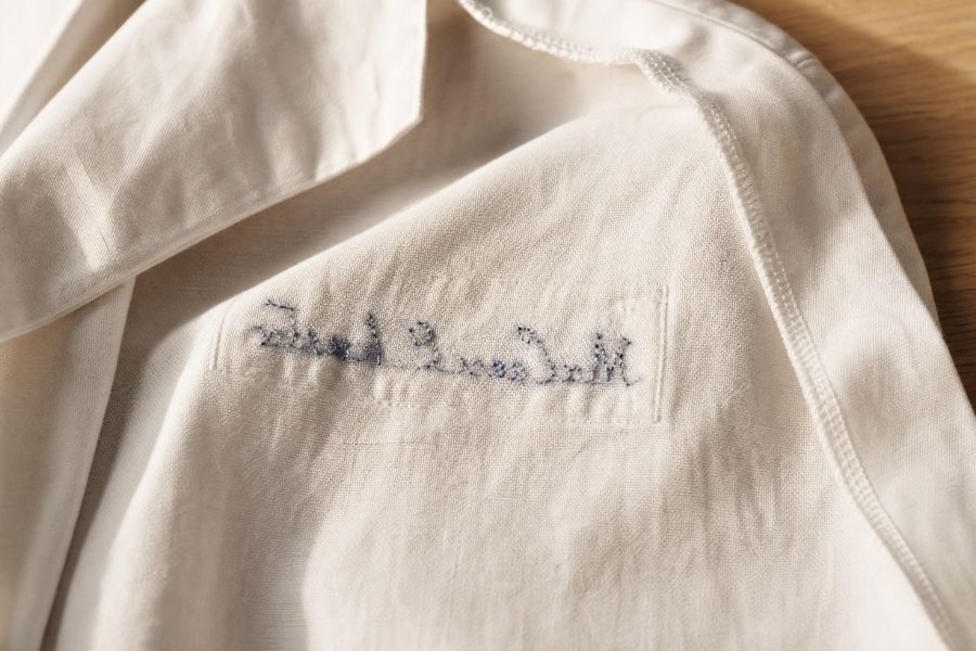 Jaleco branco do avesso mostrando o verso do bordado personalizado