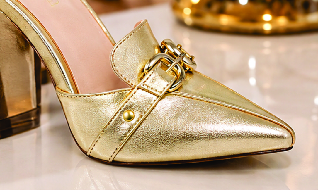 Sapato scarpin mule feminino de bico fino e salto alto revestido em napa Dourado  Torricella, com detalhe de fivelas douradas no cabedal na sala moderna e estilosa.06