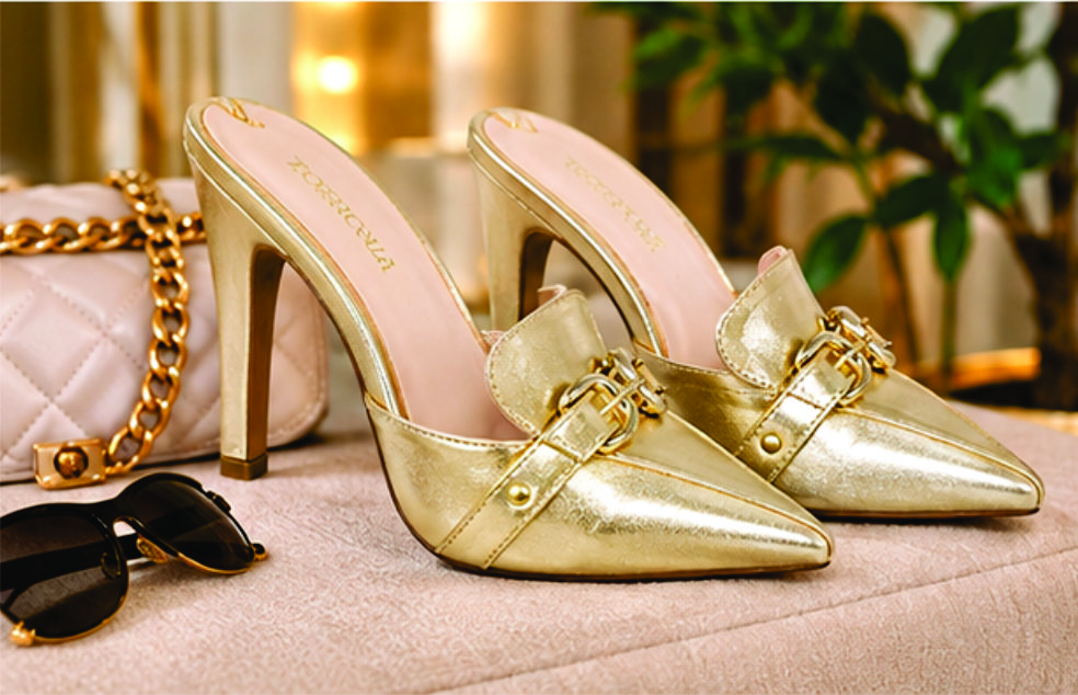 Sapato scarpin mule feminino de bico fino e salto alto revestido em napa Dourado  Torricella, com detalhe de fivelas douradas no cabedal na sala moderna e estilosa.05