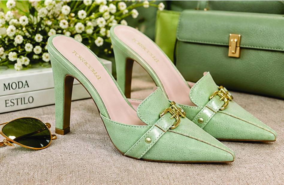Sapato scarpin mule feminino de bico fino e salto alto revestido em napa Verde Torricella, com detalhe de fivelas douradas no cabedal na sala moderna e estilosa.05