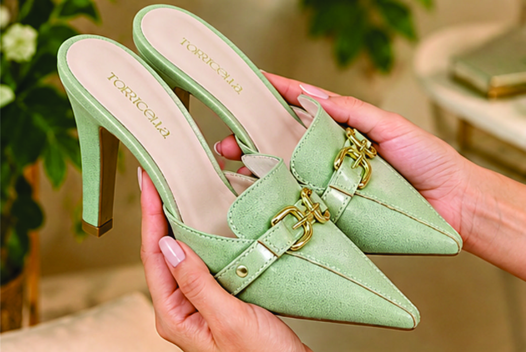 Sapato scarpin mule feminino de bico fino e salto alto revestido em napa Verde Torricella, com detalhe de fivelas douradas no cabedal na sala moderna e estilosa.01