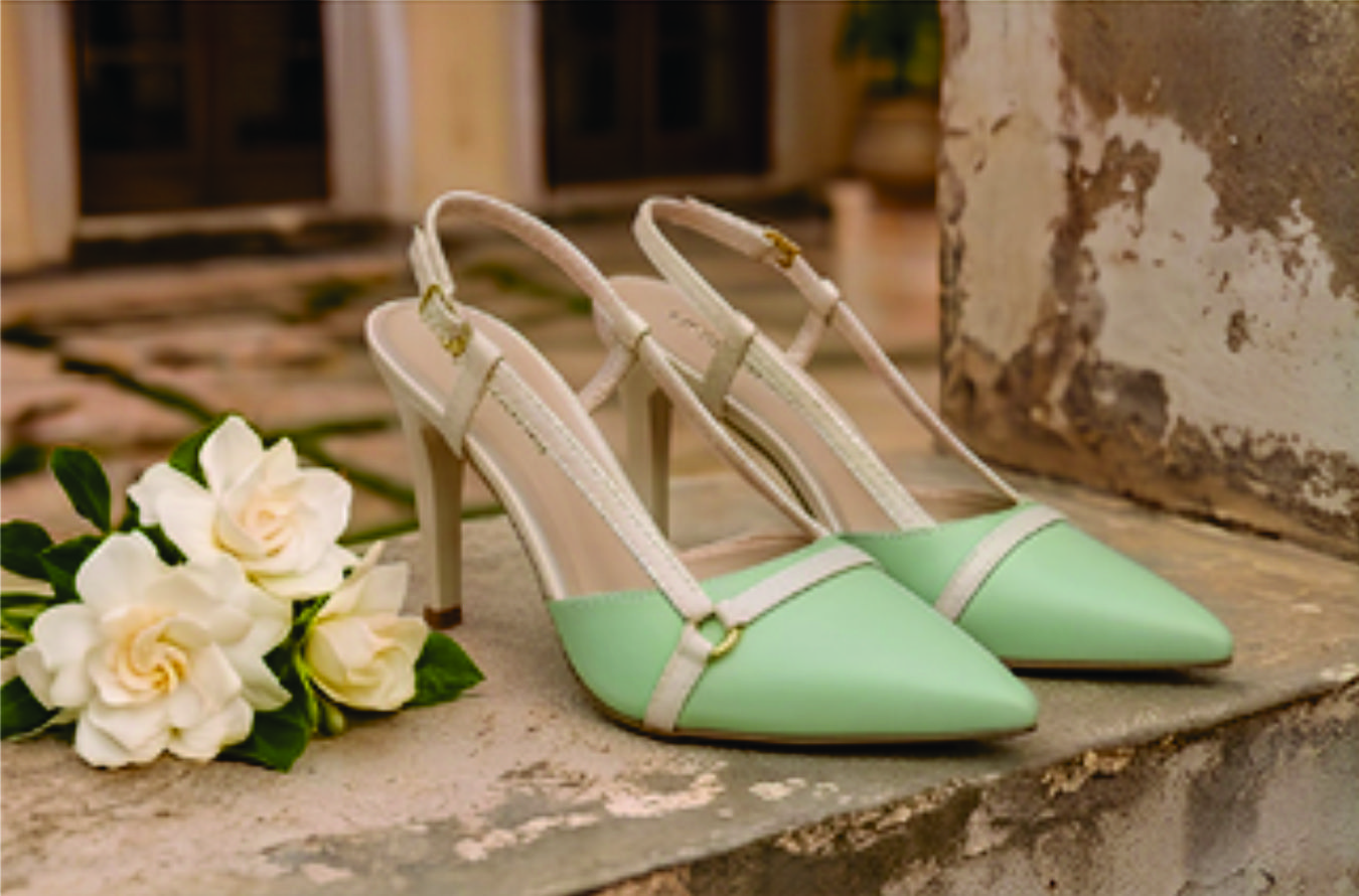 Sapato scarpin feminino modelo slingback de bico fino na cor napa Verde Torricella com fivela dourada, exposto sobre uma mesa de vidro em uma galeria de arte moderna luxuosa.
