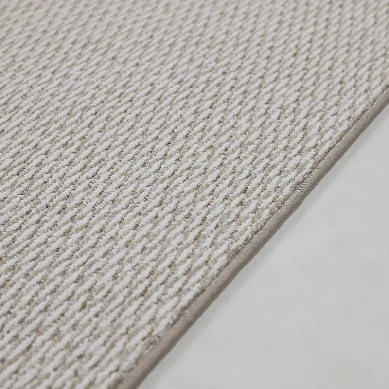 Detalhe do acabamento industrial das bordas do carpete Belgotex À La Carte com fios originais do próprio carpete