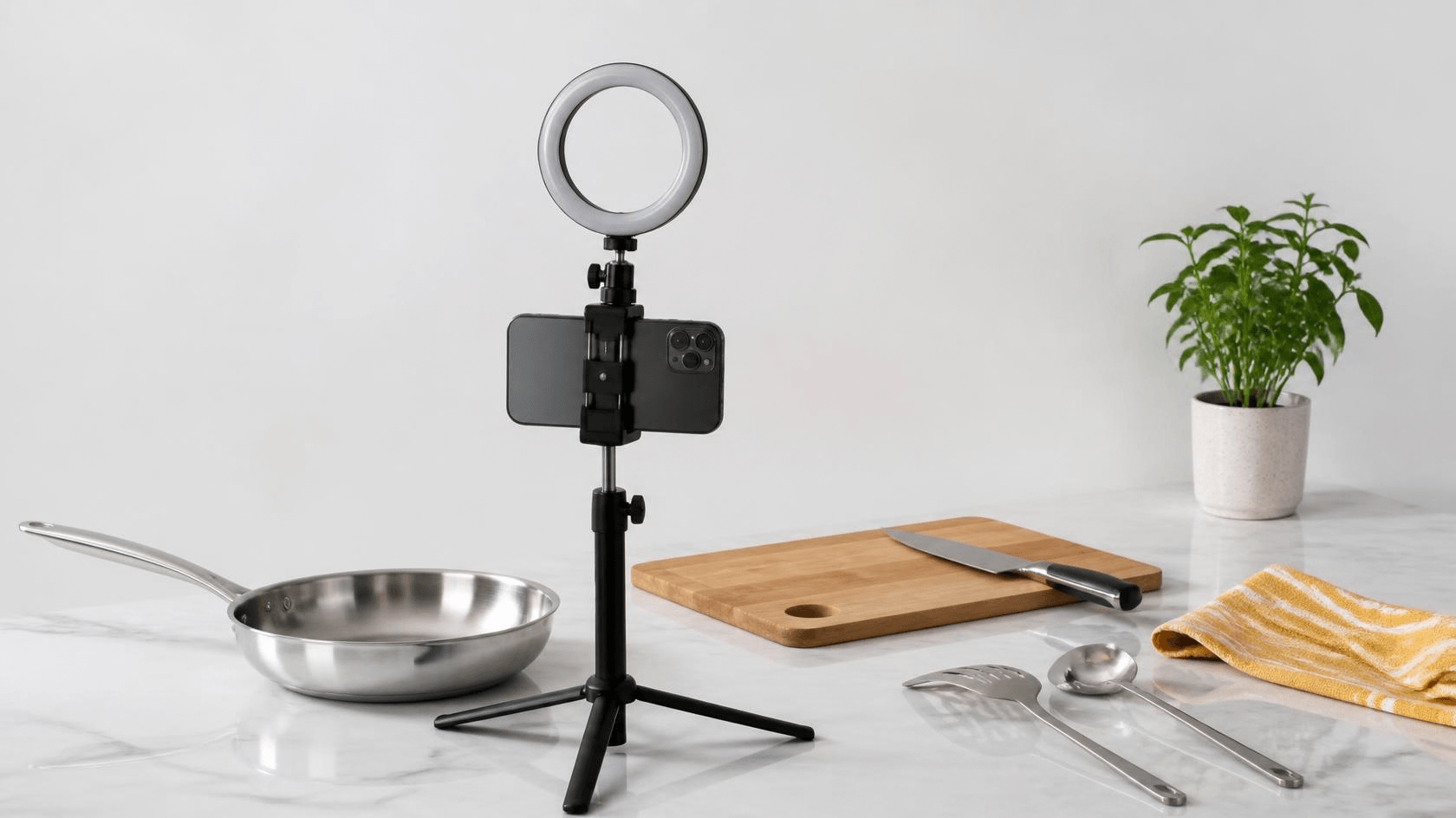 Celular em um tripé com luz de anel gravando uma bancada de cozinha com panela e utensílios de aço inox