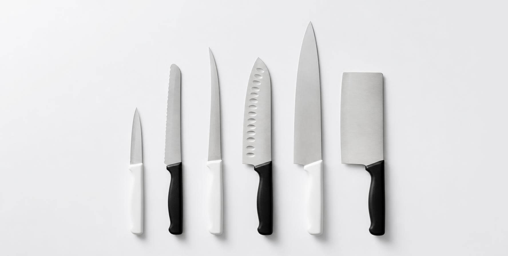 Facas de cozinha de tipos diferentes alinhadas lado a lado: chef, santoku, desossa, cutelo e faca de legumes