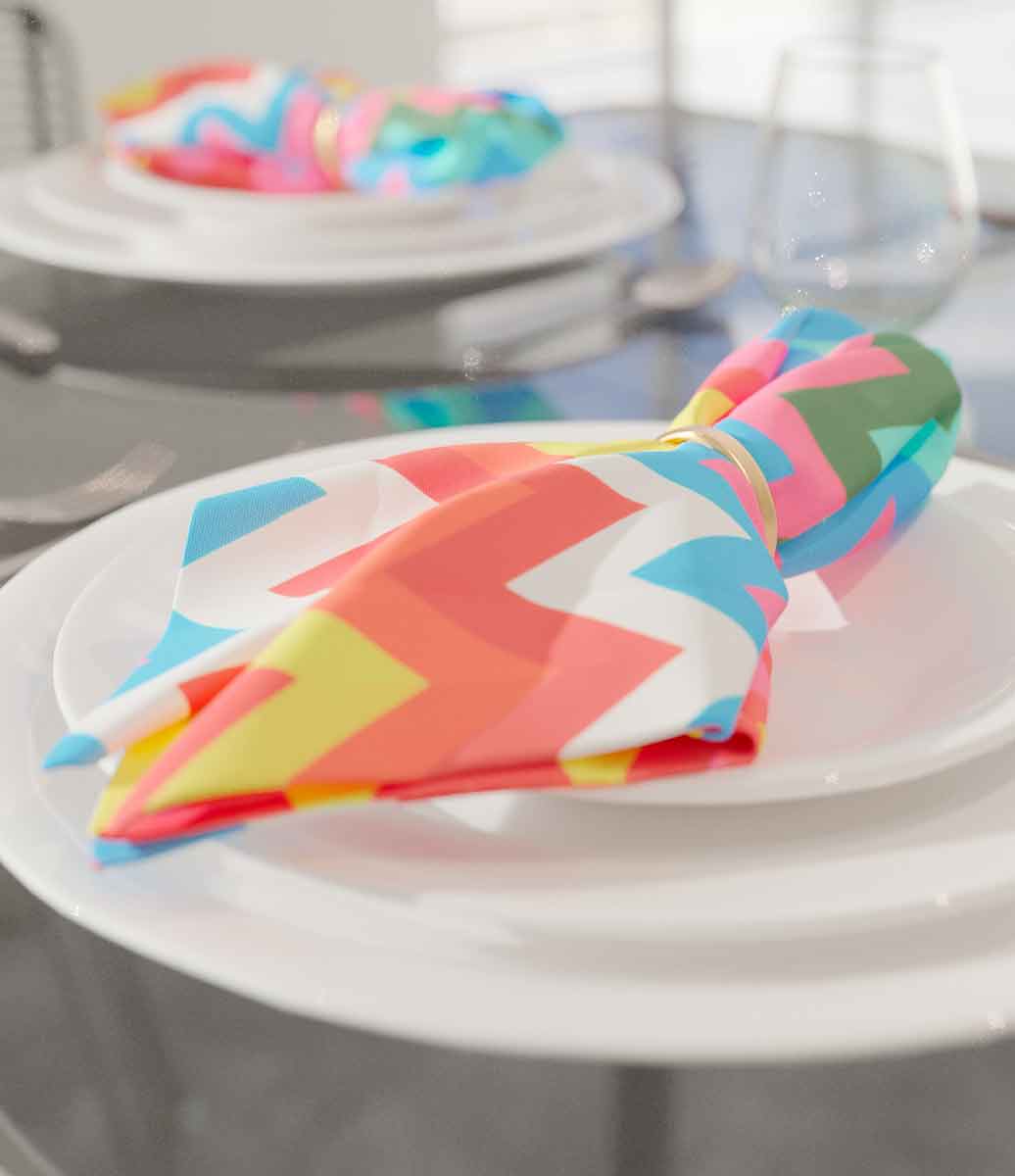 mesa decorada com louças brancas e guardanapos coloridos em estilo chevron