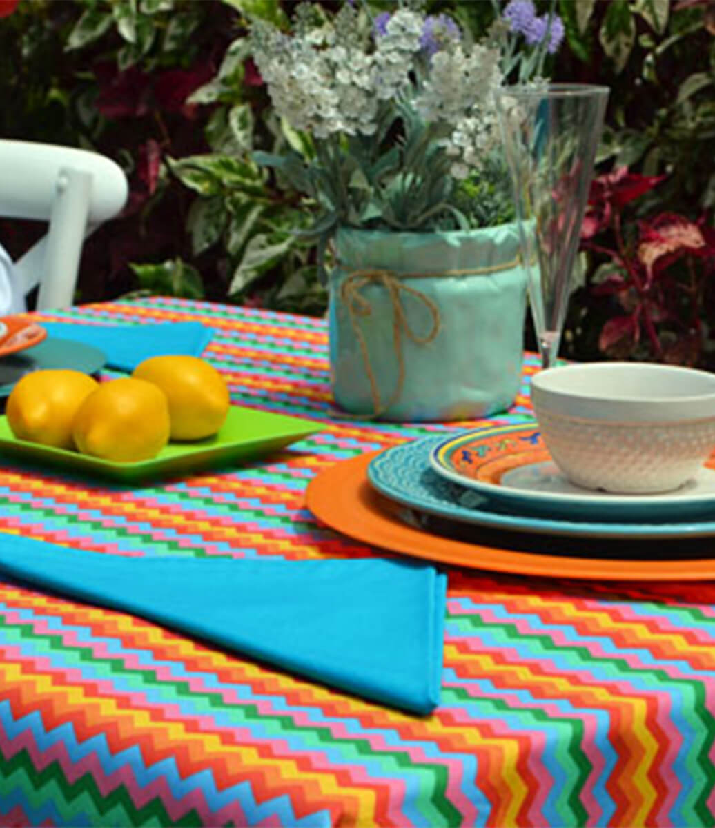 decoração de mesa com toalha de mesa laranja listrada e guardanapos azuis