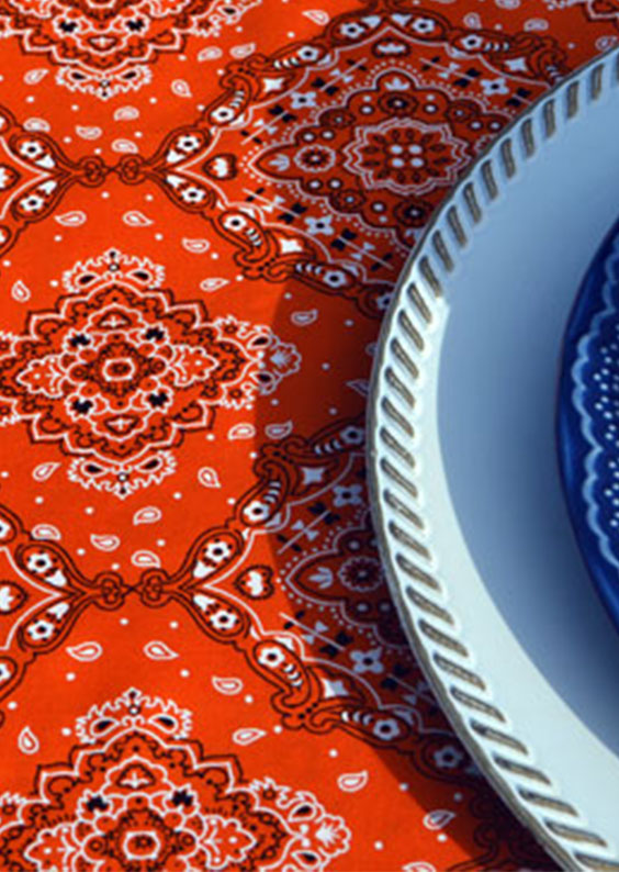 toalha de mesa laranja estampada em detalhe com louça branca
