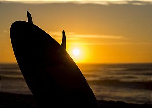 Belo pôr do sol dourado com prancha de surf e o mar