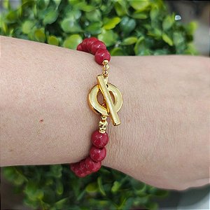 Pulseira com detalhes de resinas vermelhas ( bolinhas) e fecho T folheado em ouro