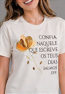 T-SHIRT FEMININA - CONFIA NAQUELE QUE ESCREVE OS TEUS DIAS - COR MARFIM