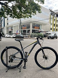 BICICLETA MTB ARO (29) OGGI HACKER HDS SHIMANO ESSA 8V FREIO DISC HIDRÁULICO TAMANHO 15 (P) COR GRAF/AMAR/PTO