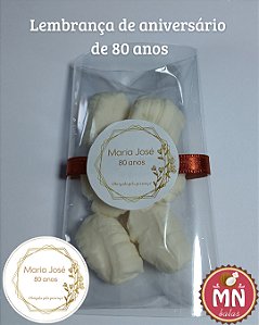 Unidade do saquinho adesivado com 6 balas de coco tradicionais, sem recheio, no tamanho normal fechados com fita de cetim número 2 com tag personalizada 3,5 cm aniversário de 80 anos