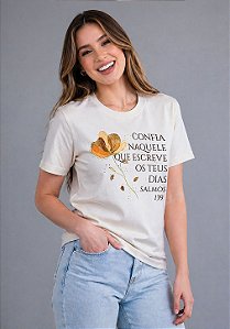 T-SHIRT FEMININA - CONFIA NAQUELE QUE ESCREVE OS TEUS DIAS - COR MARFIM
