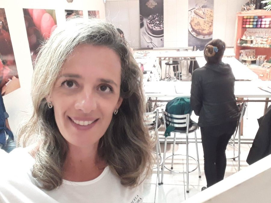 Marcela no espaço do curso, com a turma ao fundo