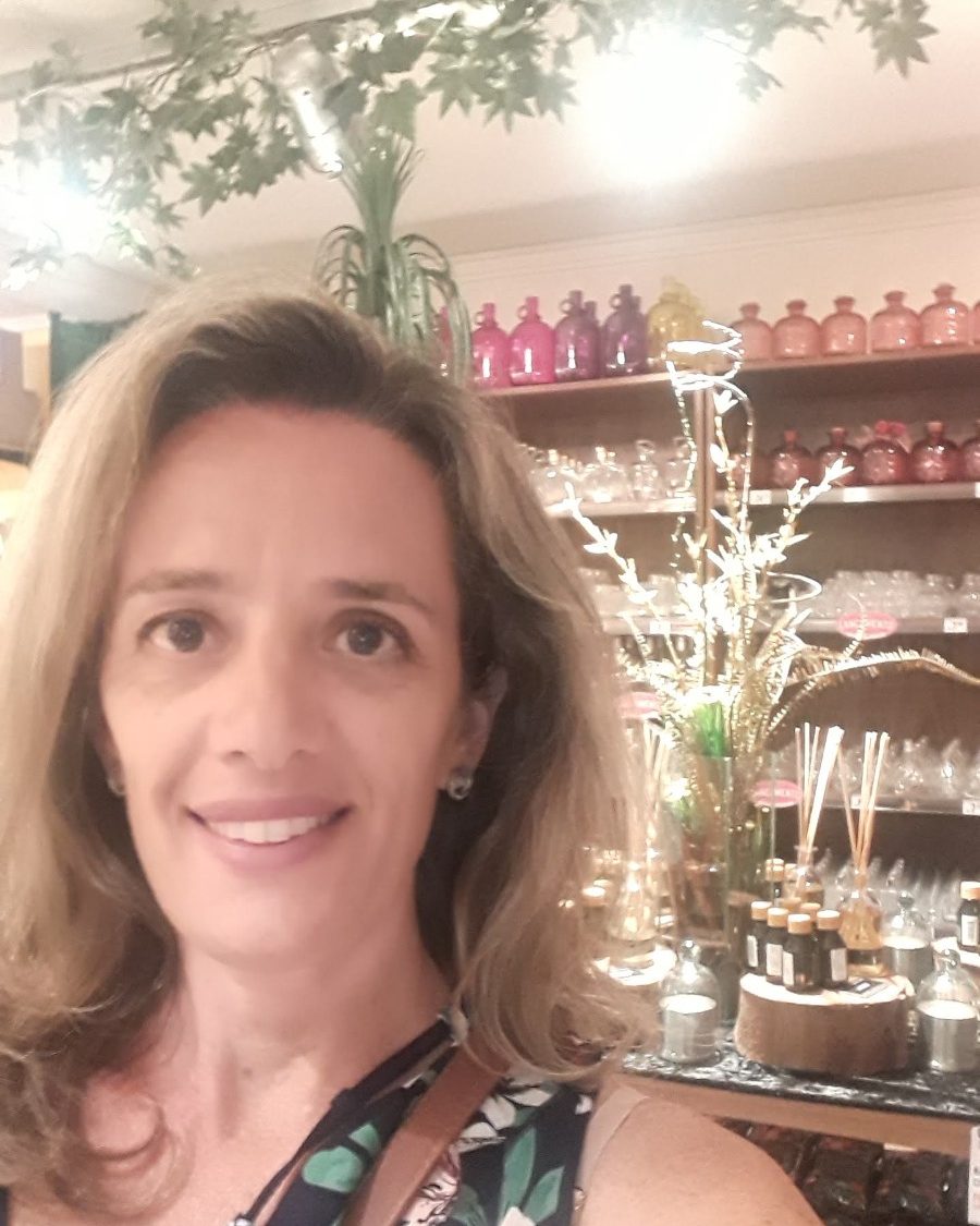 Marcela em uma loja de aromas, cercada de frascos e difusores