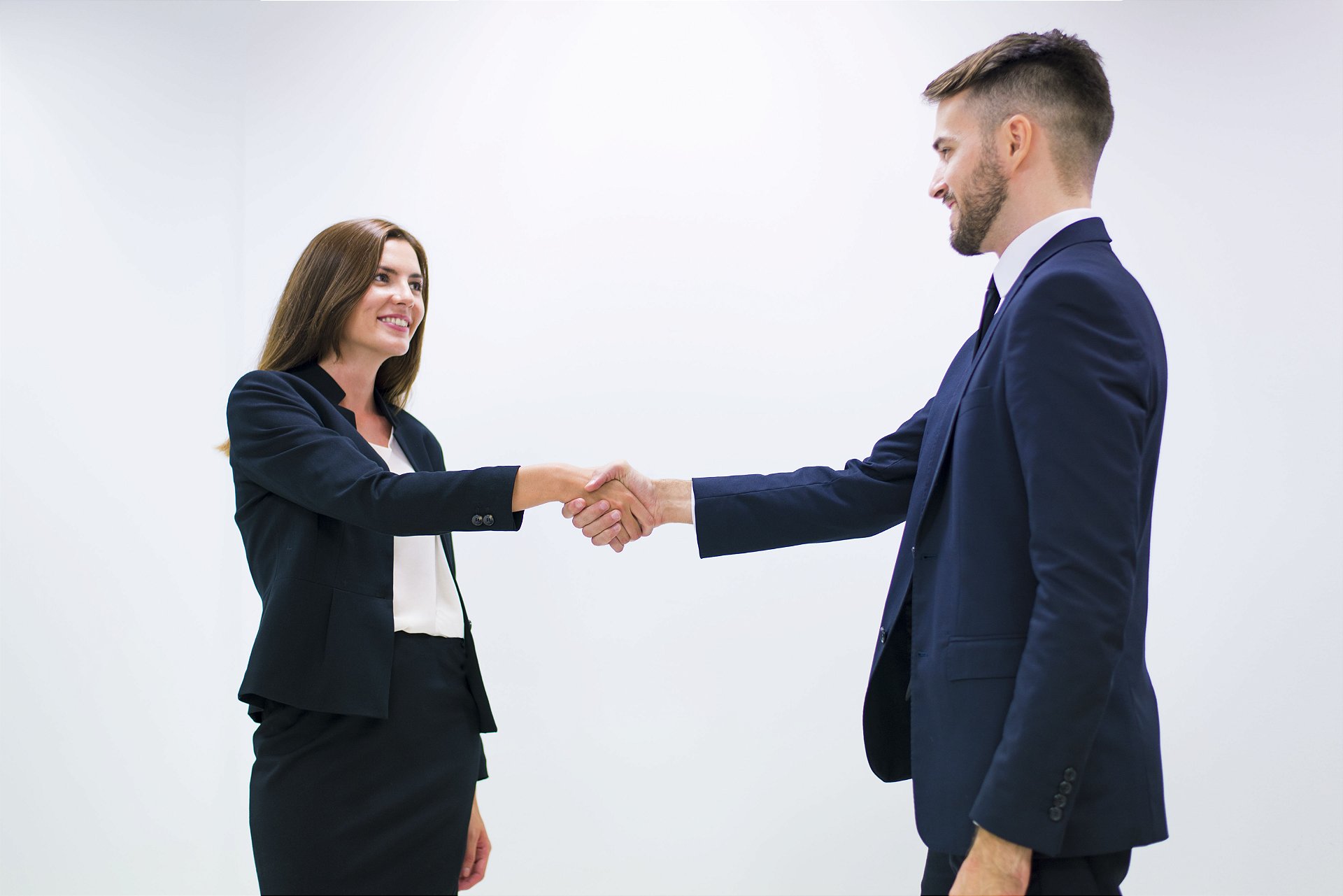 homem e mulher de terno apertando a mão