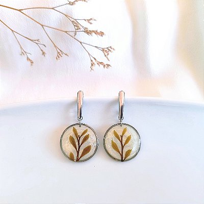 Brincos de raminho de folhas na moldura redonda