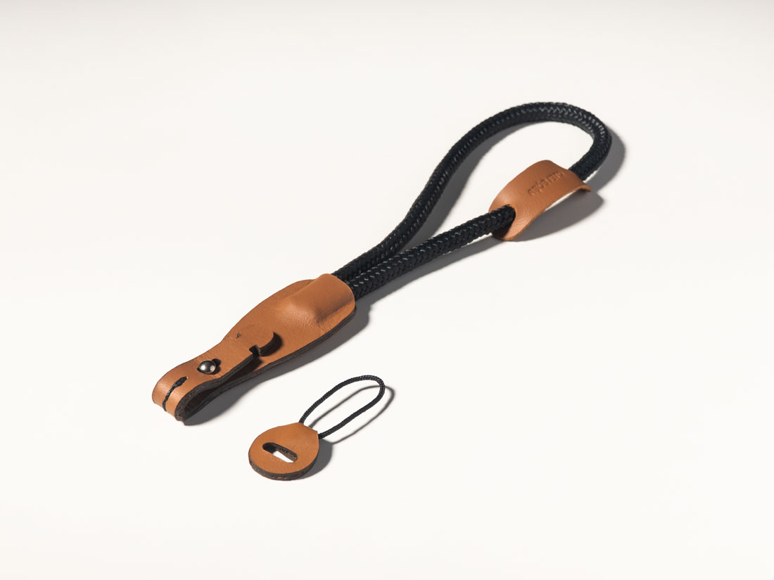 Correia para câmera em couro caramelo e corda de malha sintética preta. Correia para câmera em couro caramelo e corda de malha sintética preta.