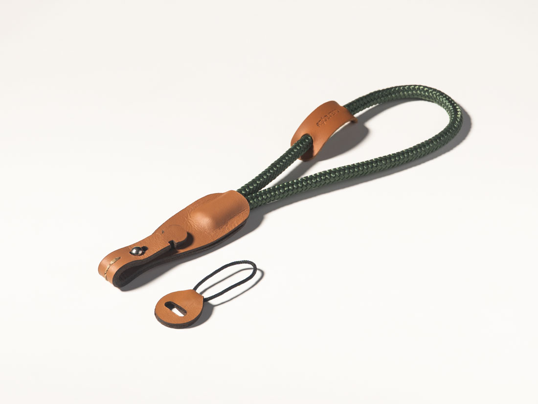 Correia para câmera em couro caramelo e corda de malha sintética verde. Correia para câmera em couro caramelo e corda de malha sintética verde.