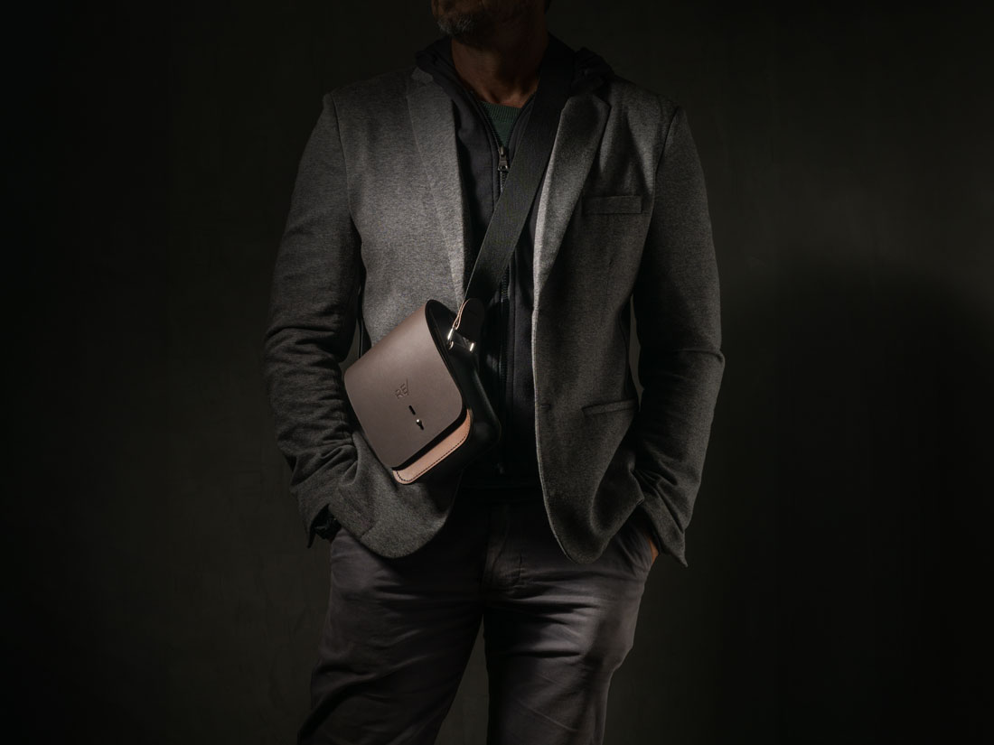 Bolsa Cube em couro bicolor marrom e preto usada a tiracolo.