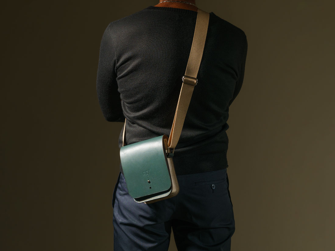 Bolsa Cube em couro bicolor verde e off-white usada a tiracolo como uma shoulder bag.