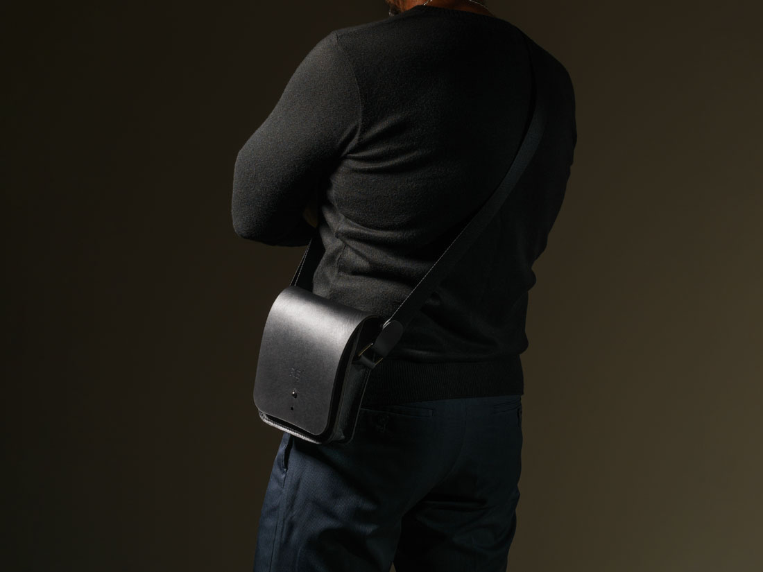 Bolsa Cube em couro preto usada a tiracolo como uma shoulder bag.