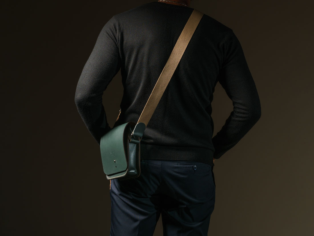 Bolsa Cube em couro verde usada a tiracolo como uma shoulder bag.