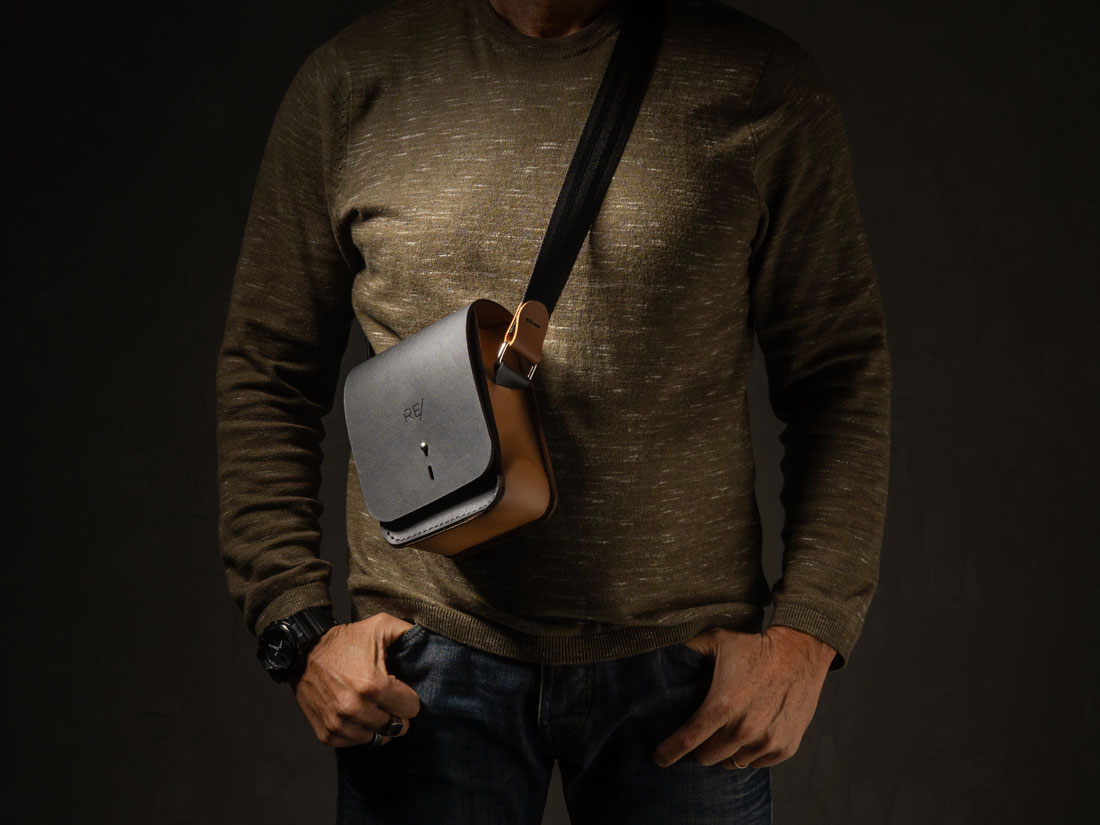 Bolsa Cube em couro bicolor preto e caramelo usada a tiracolo.