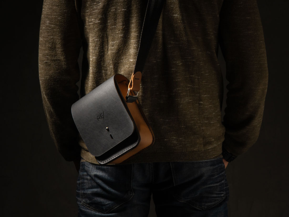 Bolsa Cube em couro bicolor preto e caramelo usada a tiracolo como uma shoulder bag.