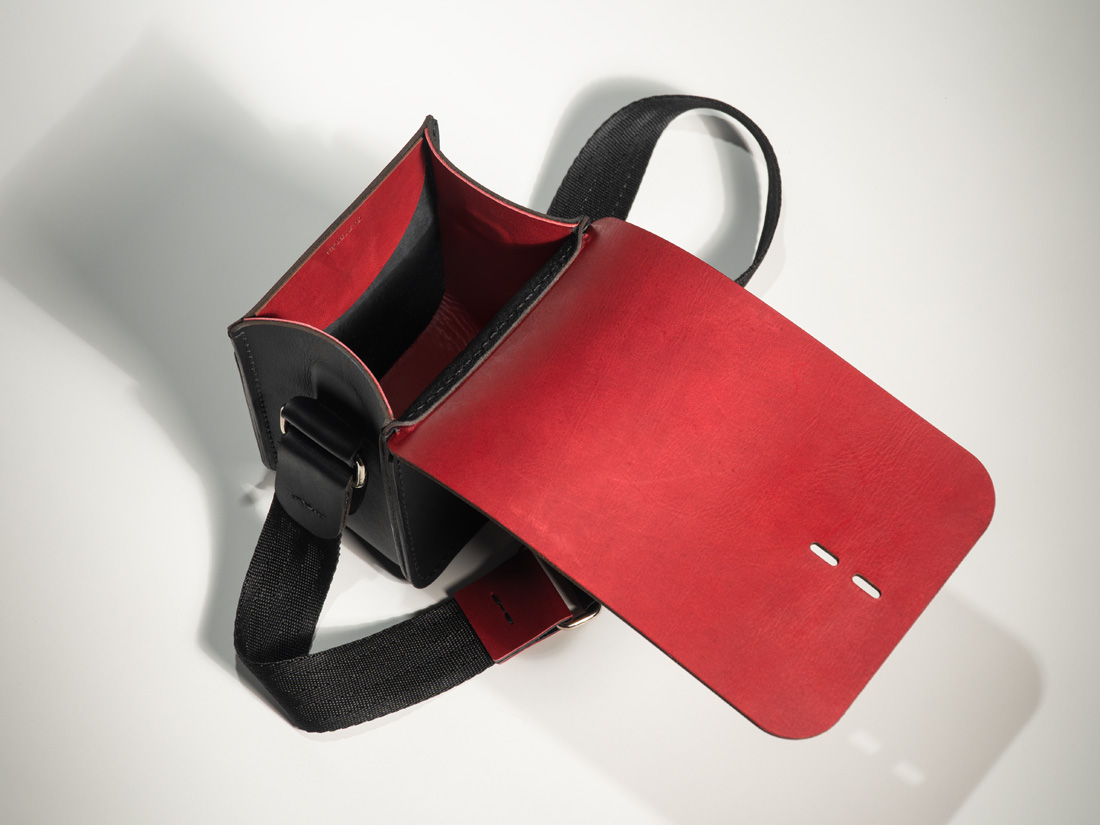 Bolsa Gran Cube aberta mostrando seu interior combinando camurça preta e forro em couro vermelho burgundy.