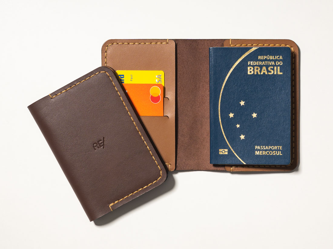Capa para passaporte feita em couro marrom café e caramelo, com slots para cartões de crédito e débito, bolsos para dinheiro em espécie e documentos.