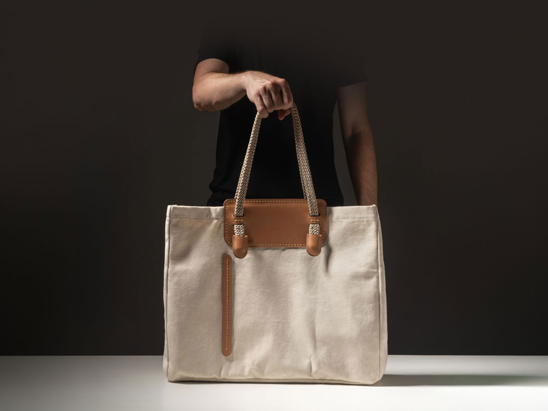 Lado posterior da bolsa Duna em couro caramelo e lona de algodão cru off-white.
