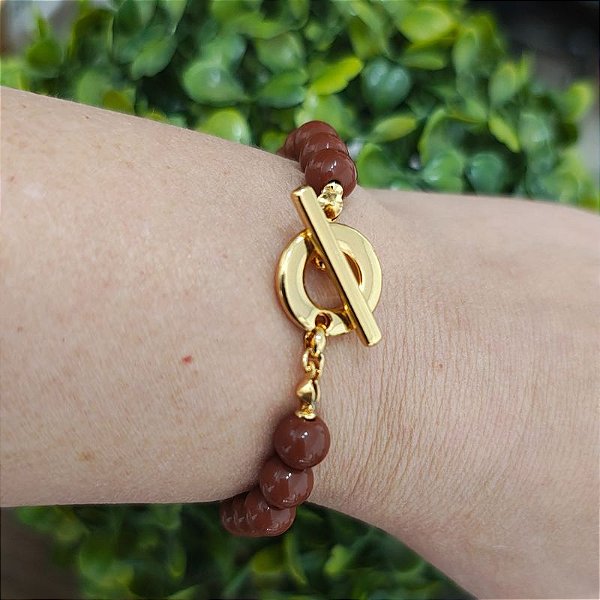 Pulseira com detalhes de resinas marrom ( bolinhas) e fecho T folheado em ouro