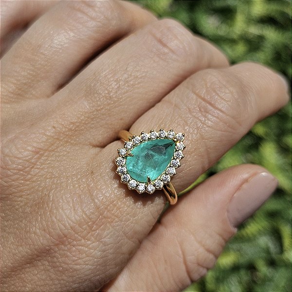 Anel dourado com pedra de zircônia verde e cravejado ao redor com micro zircônias brancas