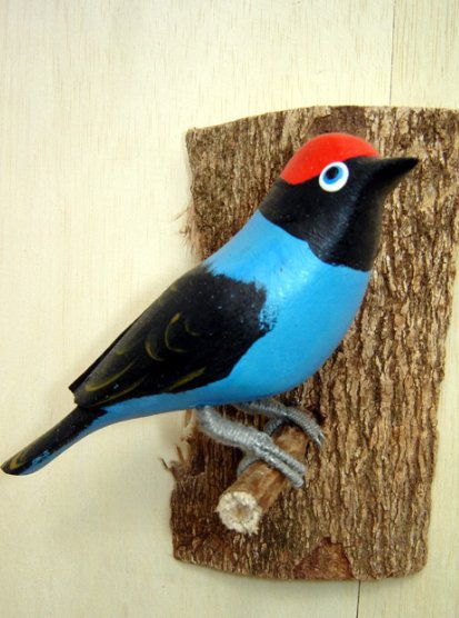 Tangará - Pássaro esculpido em madeira apoiado em um puleiro de casca de árvore