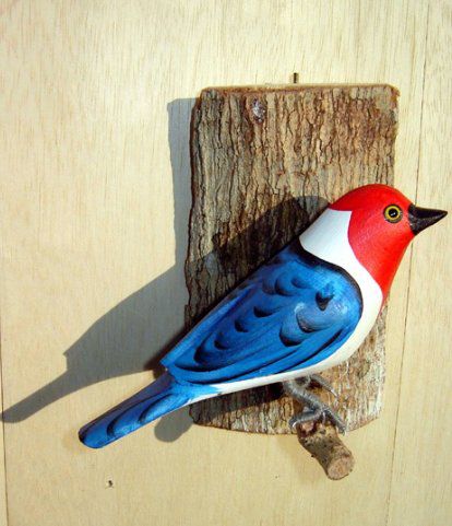 Galo de Campina - Pássaro esculpido em madeira apoiado em um puleiro de casca de árvore