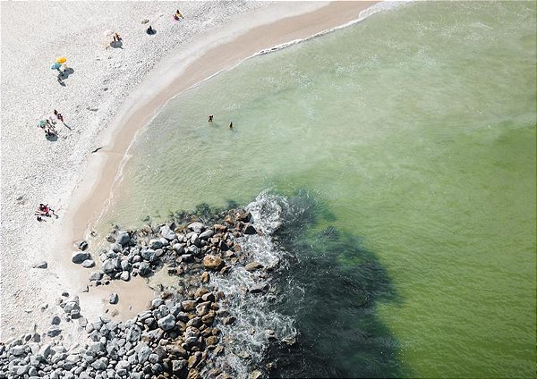 Fotografia aérea de um belo mar esmeralda pedras faixa de areia e banhistas