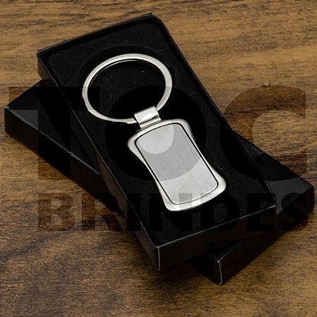 Chaveiro em aço brilhante, retangular com laterais curvadas para dentro, com chapa central fosca, argola alto brilho e caixinha em papel com berço em plástico preto aveludado