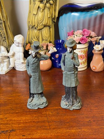 Esculturas em cerâmica de casal com trajes vitorianos.