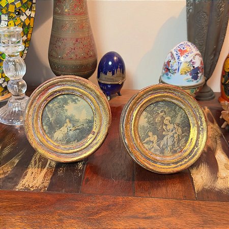 Par de antigos e pequenos quadros redondos.