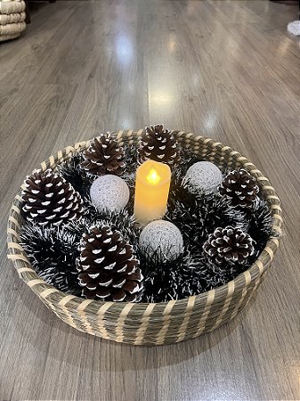 Cesto largo com pinhas e folhagem verde com neve