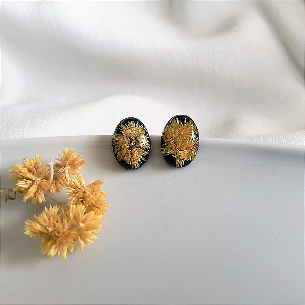 Brinco oval com macela no fundo preto