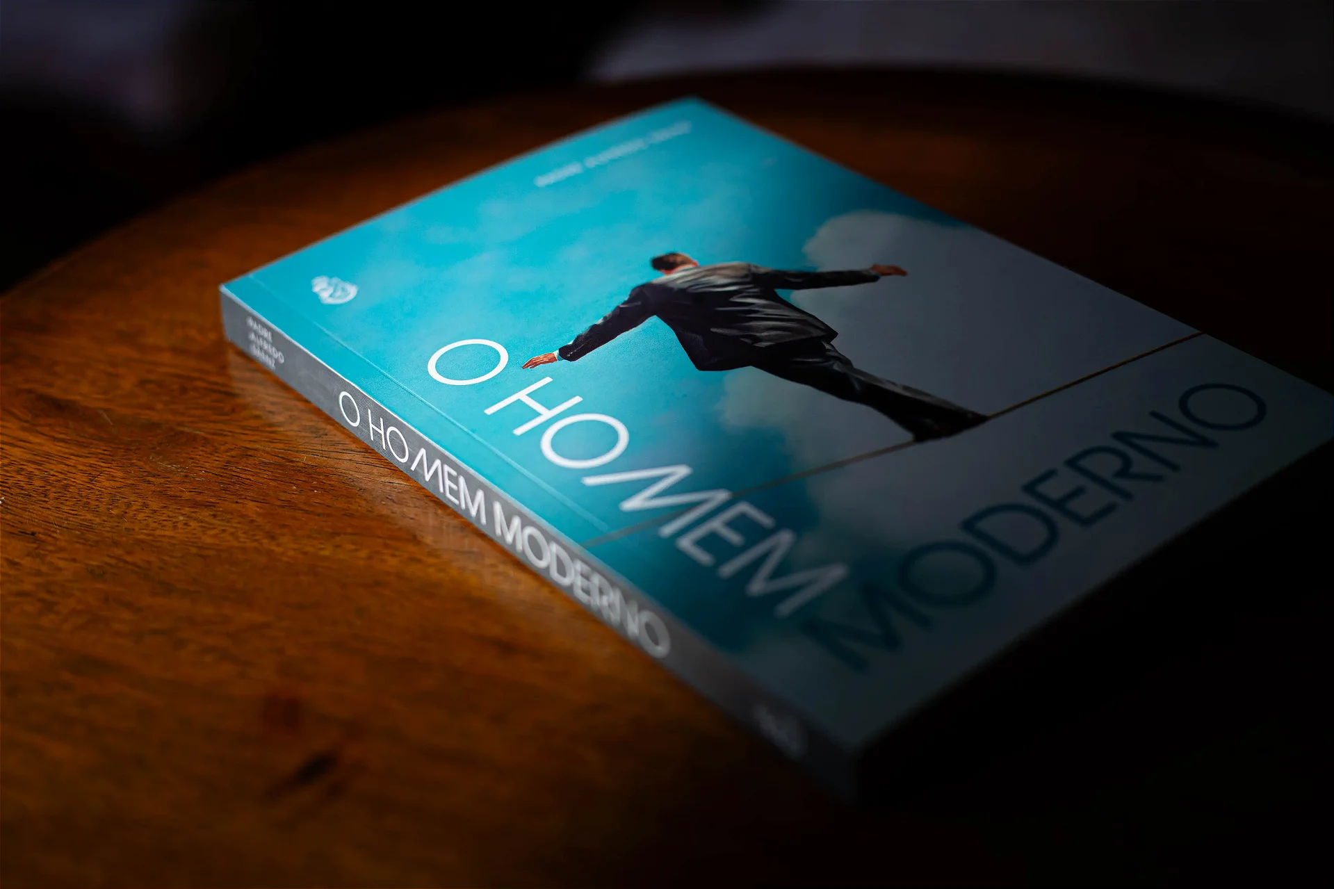 Livro O Homem Moderno deitado em ângulo, com a lombada à mostra