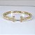 BRACELETE DOURADO ABERTO NA FRENTE COM DETALHE EM "T" COM PEDRAS DE ZIRCÔNIAS BRANCAS - Imagem 1